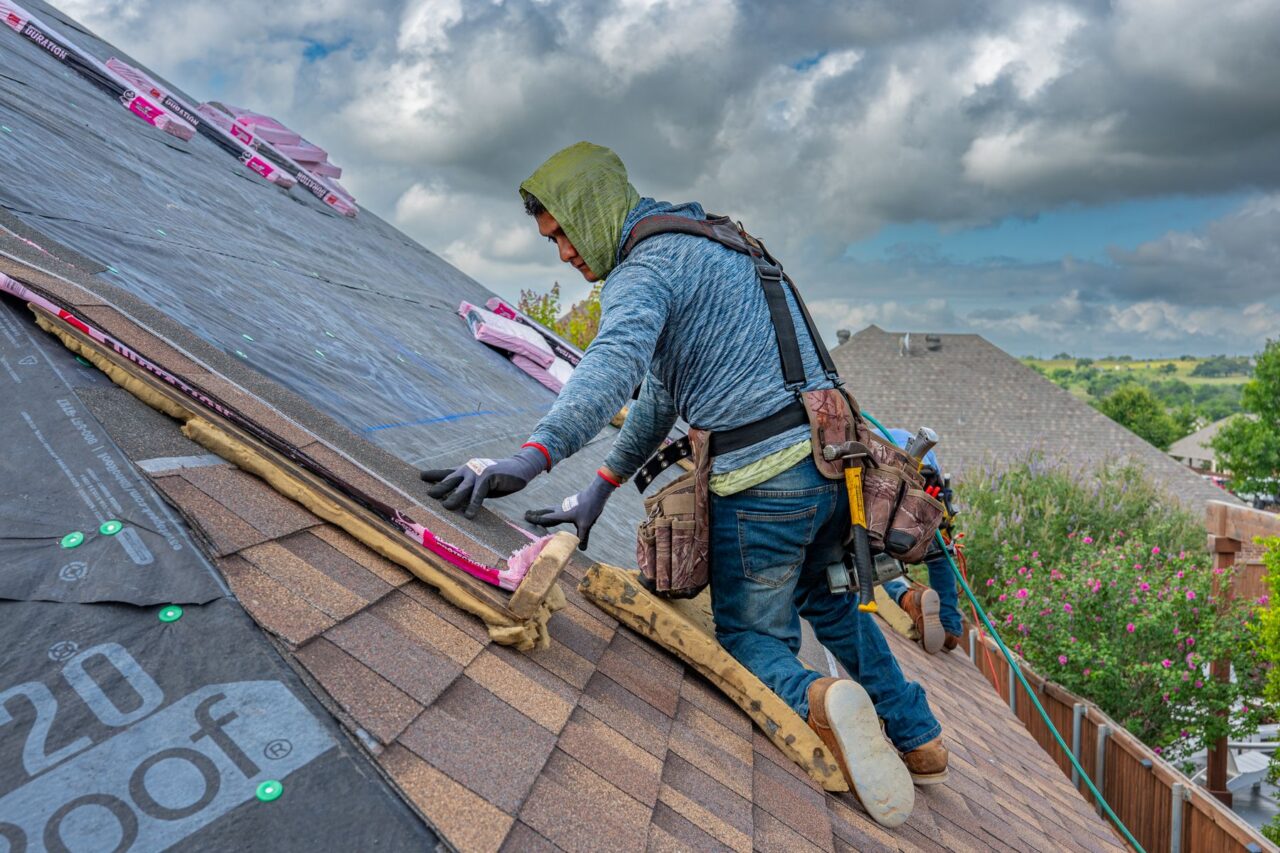 Professional roofer working safely on asphalt shingles